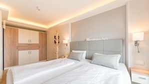 A modern hotel room with a large bed, a wardrobe, and a headboard with the word 'Meeresauschen'.