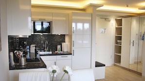 A modern kitchen with white cabinets, a black countertop, and a built-in microwave.