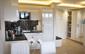 A modern kitchen with white cabinets, a black countertop, and a built-in microwave.