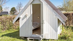 A small, single-room shed with a slanted roof, a door, and a bench outside. - Beautiful home in Stubbekøbing with WiFi (Stubbekøbing)