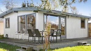 A modern, single-story house with a covered patio area featuring a table and chairs. - Beautiful home in Stubbekøbing with WiFi (Stubbekøbing)