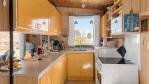 A compact kitchen with yellow cabinets, a white refrigerator, and a window with curtains. - Beautiful home in Stubbekøbing with WiFi (Stubbekøbing)