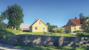 Keltainen talo, jonka edessä on kivimuuri, punainen katto ja vihreä nurmikko.