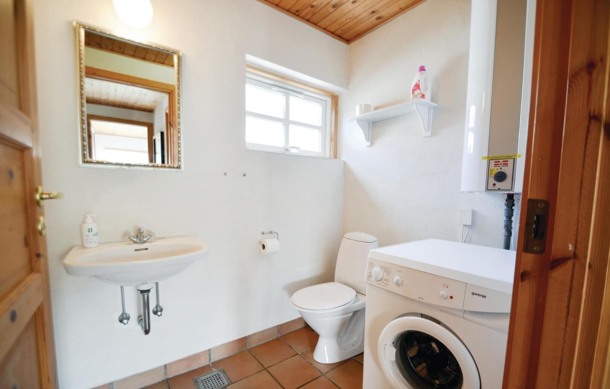 Ein kleines Badezimmer mit Waschbecken, Toilette und Waschmaschine.