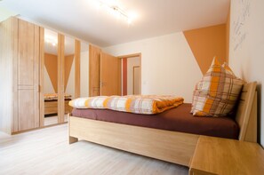A bedroom with a bed, wooden wardrobe, and a mirror. - Vacation apartment Lahner (Königsfeld)