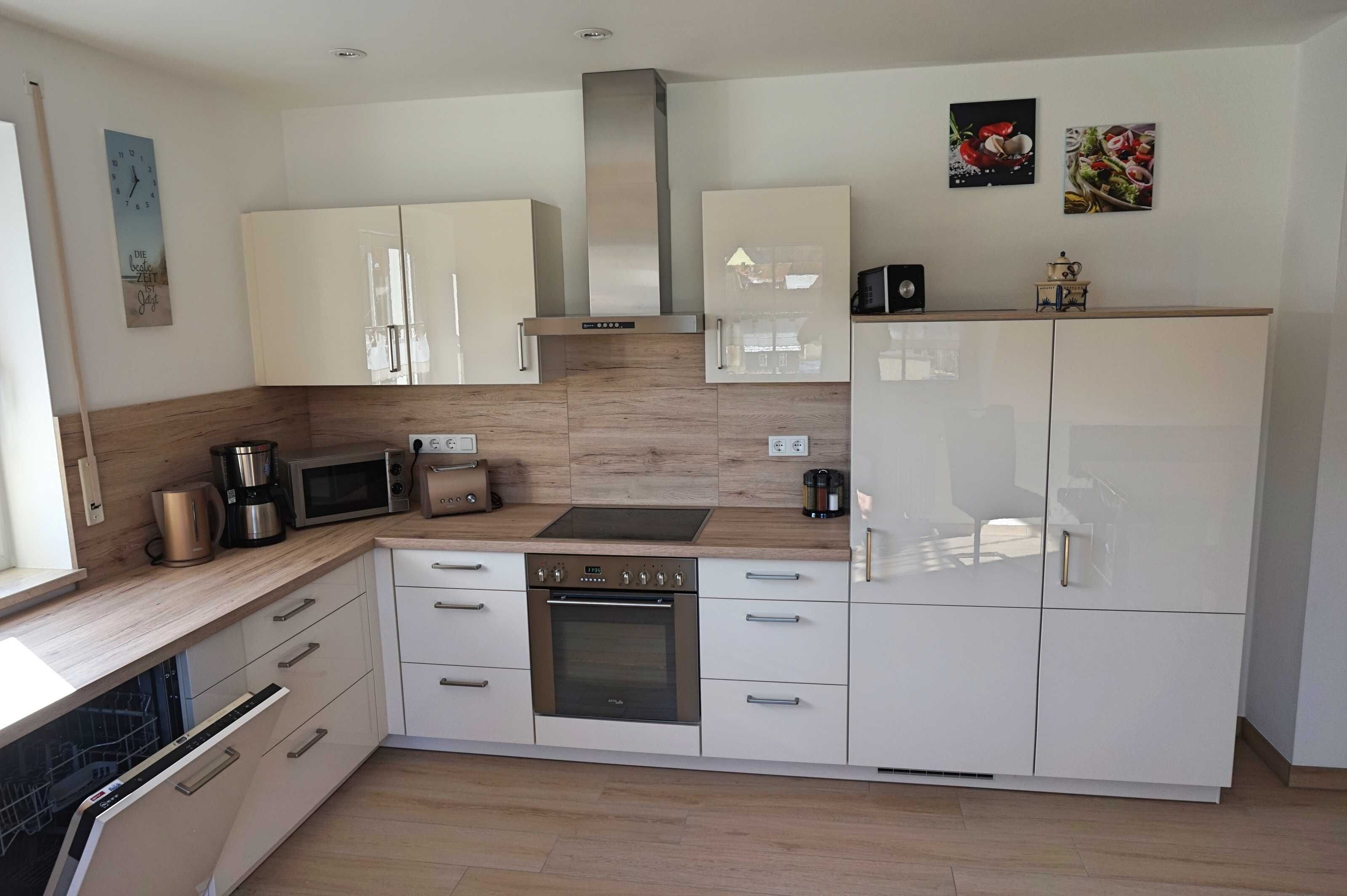 A modern kitchen with white cabinetry, a built-in oven, a microwave, and a coffee maker.