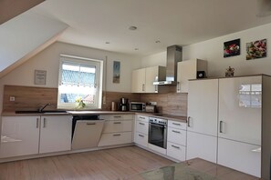 A modern kitchen with white cabinetry, a built-in oven, and a microwave. - Vacation apartment Lahner (Königsfeld)