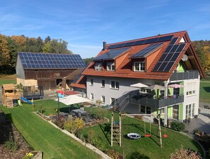 A house with solar panels, a wooden barn, a play area, and a garden. - Vacation apartment Lahner (Königsfeld)