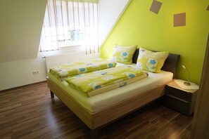 A bedroom with a bed, a nightstand, a lamp, and a window with blinds. - Vacation apartment Lahner (Königsfeld)