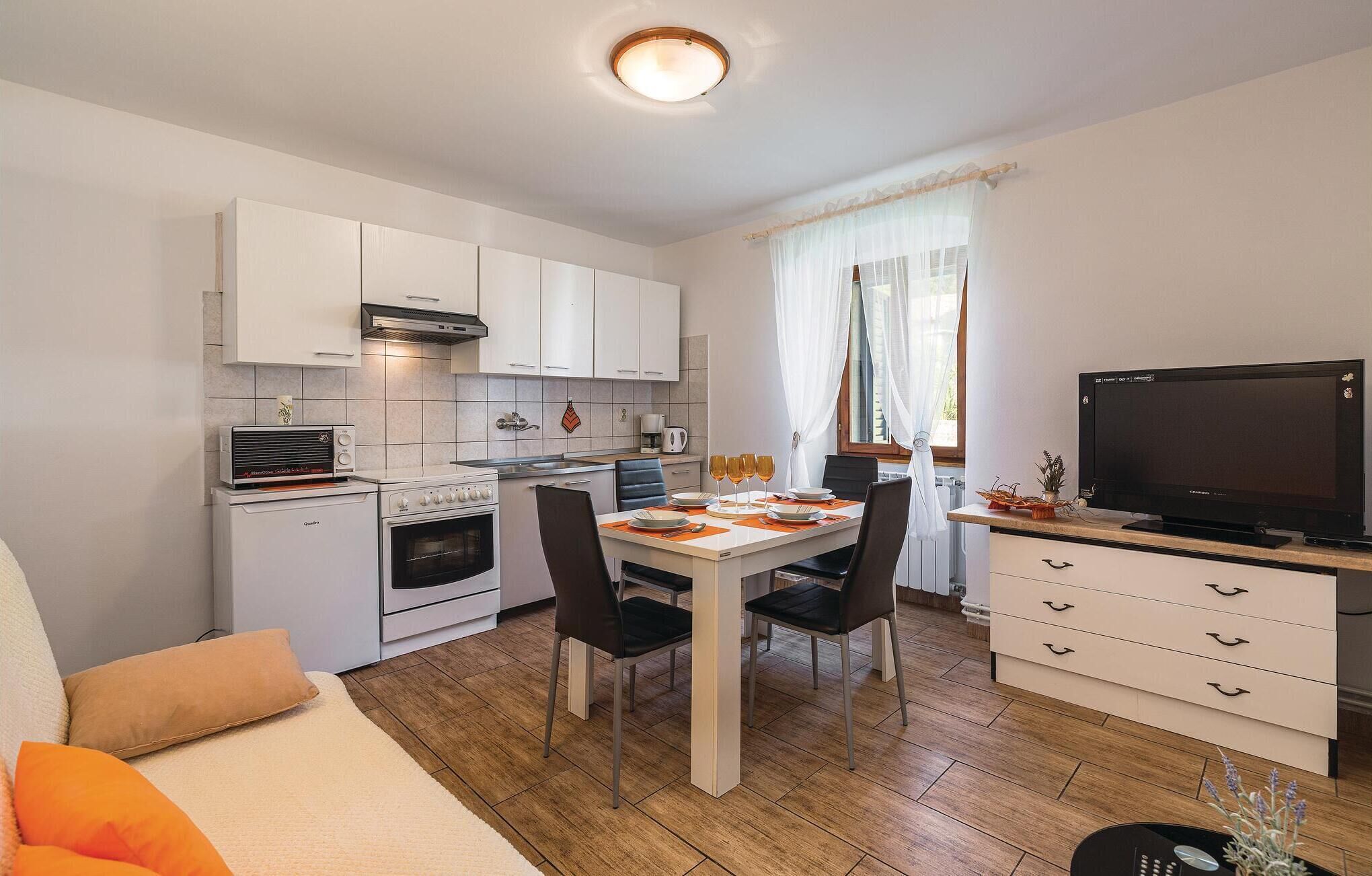 Een compacte keuken met witte kasten, een fornuis en een eethoek met een tafel voor vier personen.