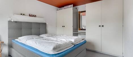 Un dormitorio con cama, armario y luz en el techo.