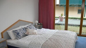 Une chambre d’hôtel avec un lit, une table de chevet, une lampe et une vue sur l’extérieur.
