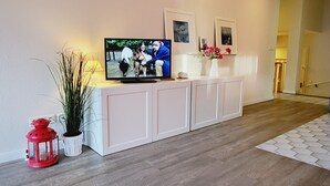 Un salon moderne avec un téléviseur posé sur un meuble blanc, une lanterne rouge et une plante en pot.