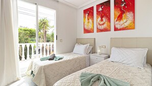 A hotel room with two beds, a balcony with a view of palm trees, and three abstract paintings on the wall. - Cozy apartment in Guardamar del Segura (Guardamar del Segura)