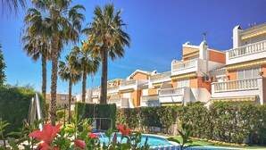 A hotel with multiple balconies, a swimming pool, and palm trees. - Cozy apartment in Guardamar del Segura (Guardamar del Segura)