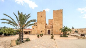 A historic building with two towers, a cobblestone pathway, and palm trees. - Cozy apartment in Guardamar del Segura (Guardamar del Segura)