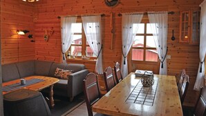 Een gezellig interieur van een chalet met een houten eettafel, een bank en een kroonluchter.
