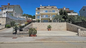 A multi-story building with balconies, a stone wall, and potted plants.