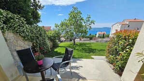 A patio with a table and chairs, a stone wall, and a view of the sea and buildings.