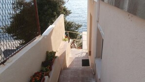 A narrow outdoor corridor with tiled flooring, a metal railing, and potted plants. - Amazing home in Podstrana with WiFi (Podstrana)