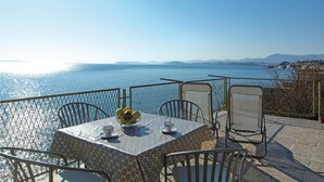A table with chairs and a tablecloth, overlooking a body of water with a distant shoreline. - Amazing home in Podstrana with WiFi (Podstrana)