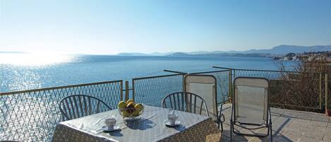 A table with chairs and a tablecloth, overlooking a body of water with a distant shoreline.