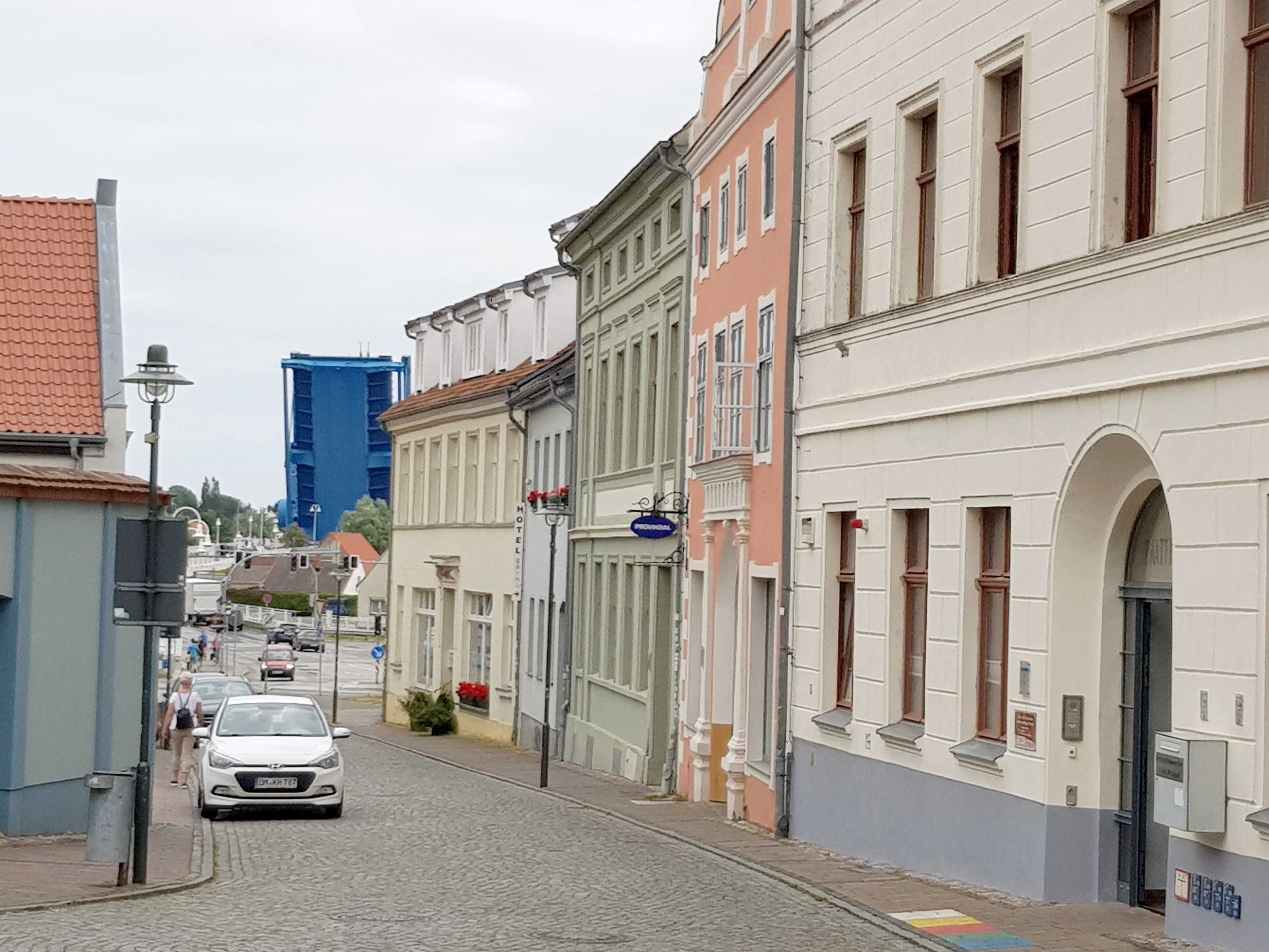 A narrow cobblestone street lined with historic buildings, including a hotel with a sign indicating it is a hotel.