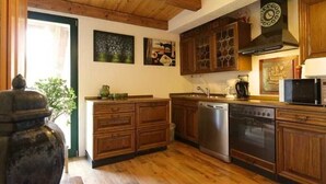 A kitchen with wooden cabinets, stainless steel appliances, and a wooden ceiling. - Apartment 2 - Fewos "Storchenhof" near the lake (Meesiger)