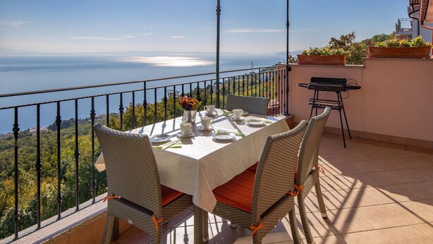 Una terraza con una mesa dispuesta para cuatro, con vistas a un paisaje marino.