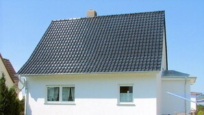 A two-story house with a tiled roof, white walls, and a brick foundation. - Wede, WH - Residential building, Germany (Ückeritz)