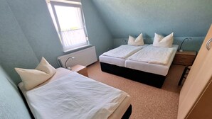 A bedroom with two beds, a window, a radiator, and a desk. - Wede, WH - Residential building, Germany (Ückeritz)