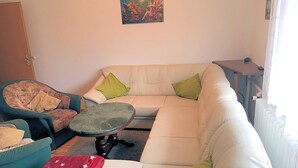 A living room with a sofa, a chair, a small table, and a red blanket. - Wede, WH - Residential building, Germany (Ückeritz)