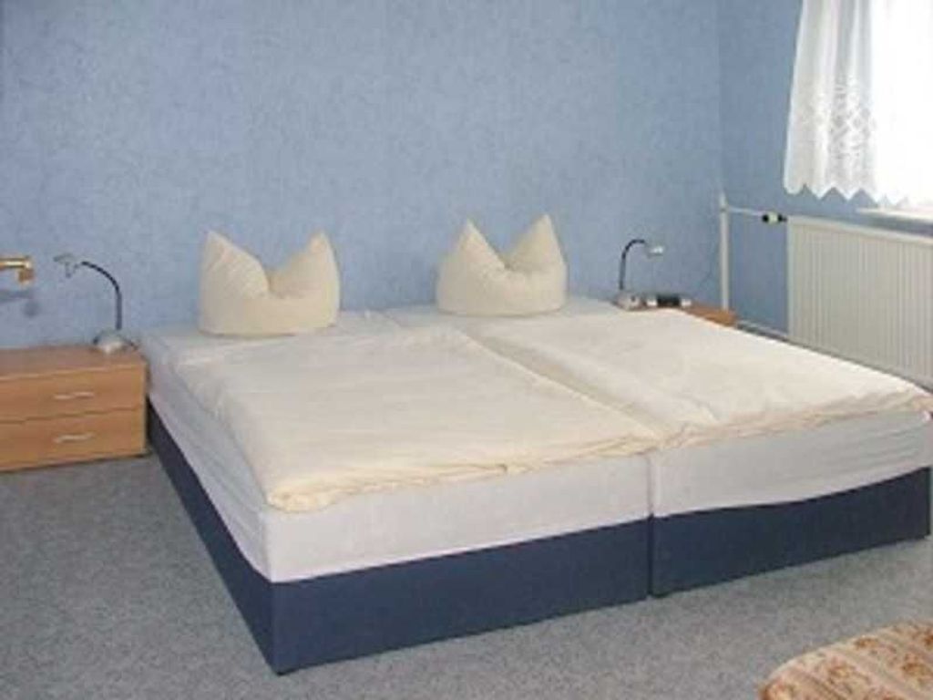 A bedroom with a bed, nightstands, and a window with curtains.