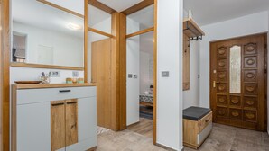 Een moderne badkamer met een houten wastafelmeubel, een grote spiegel en een douchehoek.