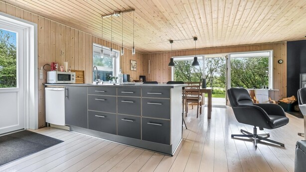 Eine moderne Küche mit Holzvertäfelung, einer zentralen Kochinsel mit Schubladen, einer Mikrowelle und einem Spülbecken.