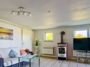 A living room with a sofa, a glass coffee table, a fireplace, a television, and a painting on the wall.