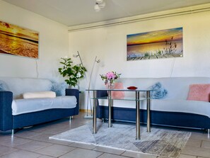A modern living room with two sofas, a glass coffee table, and decorative plants.