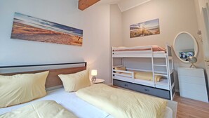 Ein Schlafzimmer mit Etagenbetten, einem Nachttisch mit Lampe und zwei an der Wand hängenden Bildern.