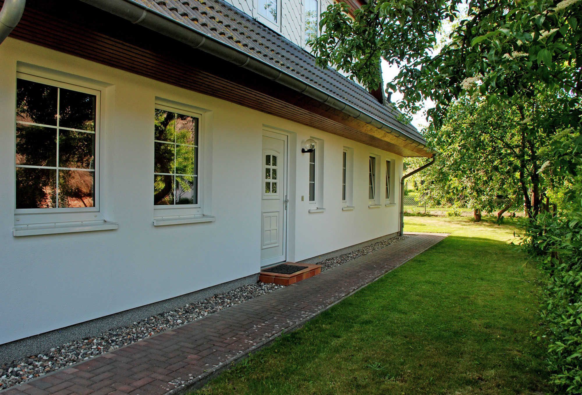 Ein weißes Gebäude mit vielen Fenstern und einem Ziegelweg, der zum Eingang führt.