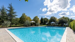 Ein rechteckiger Pool mit klarem, blauem Wasser, umgeben von einer Steindeckfläche.