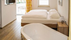 Ein Schlafzimmer mit einem großen Bett, einer Badewanne und einem Fenster mit Vorhängen.
