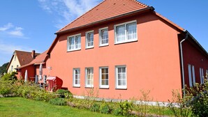 A red two-story house with white-framed windows and a red roof. - 01 Double Room B - The small hotel and apartments on Mönchgut! (Mönchgut)