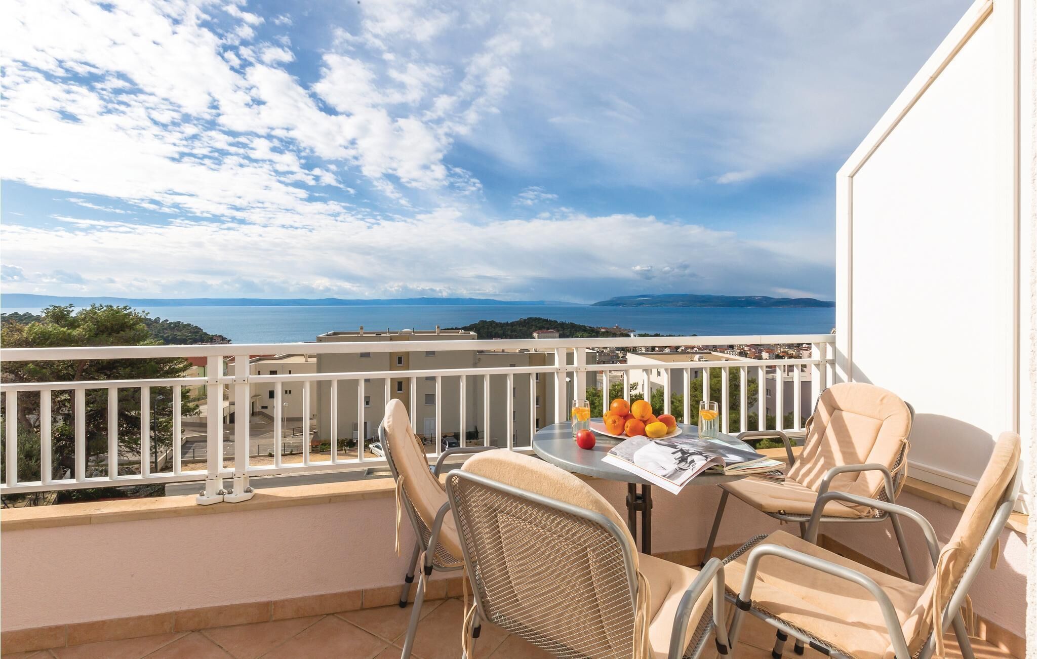 A balcony with a table, chairs, and a view of the sea.