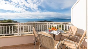 Ein Balkon mit Tisch, Stühlen und Meerblick.
