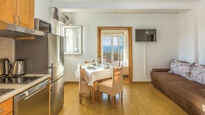 Eine kompakte Küche mit modernen Geräten, ein Essbereich mit Ausblick und ein gemütlicher Wohnraum.
