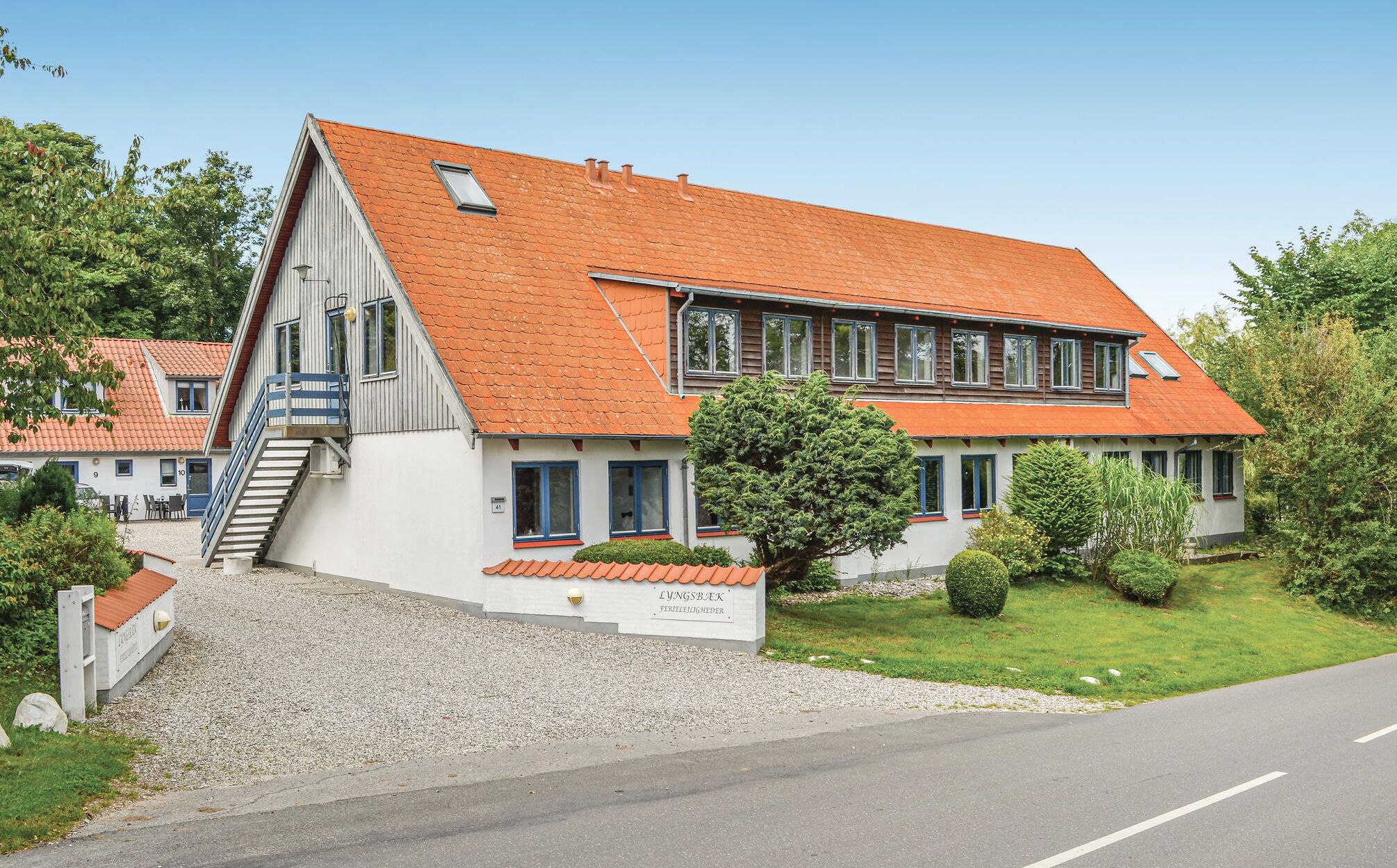 A two-story building with a sloped roof, a staircase leading to the upper floor, and a well-maintained lawn.