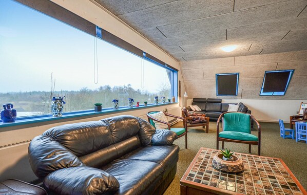 Relax in a serene forest view room with a comfortable sofa, coffee table, and armchair.