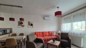 A modern living room with a sofa, armchairs, a coffee table, and pendant lights. - Holiday apartment with pool Wi-Fi and tasteful decoration (Siófok)