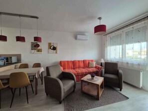 A modern living room with a sofa, armchairs, a coffee table, and pendant lights.