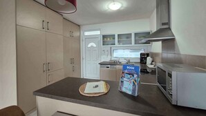 A kitchen with a microwave, a coffee maker, and a book on the counter. - Holiday apartment with pool Wi-Fi and tasteful decoration (Siófok)